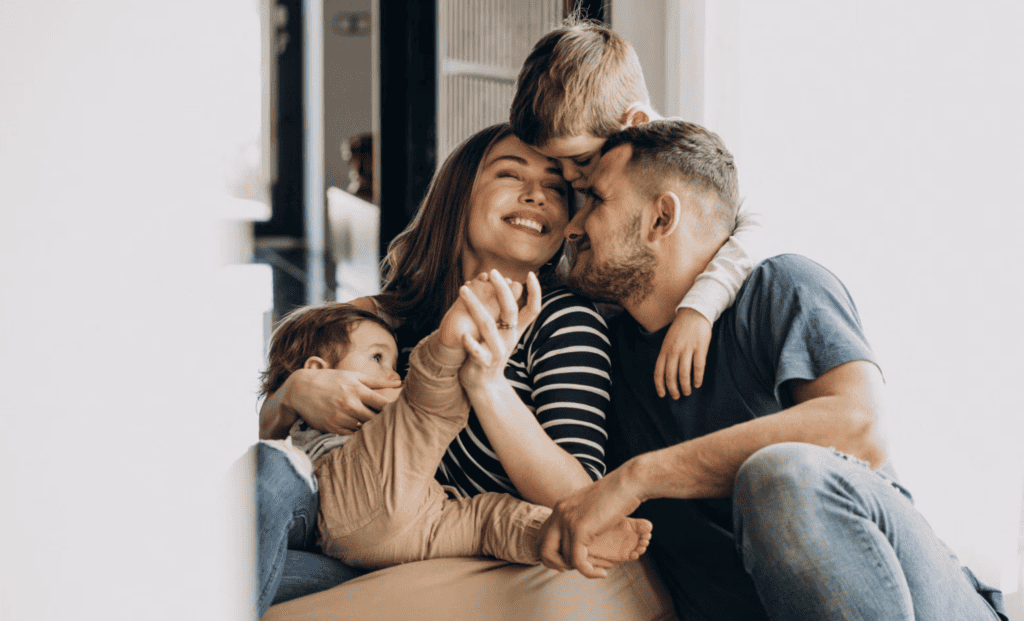Famille souriante partageant un moment de tendresse à la maison, symbole de bonheur et de complicité.