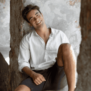 Homme portant une chemise blanche avec short, look estival décontracté et élégant assis en extérieur