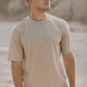 Homme portant un t-shirt beige avec lunettes de soleil, look estival décontracté et moderne en extérieur