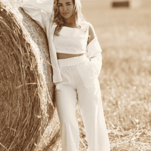 Femme portant un pantalon blanc fluide taille haute, tenue estivale élégante dans un champ