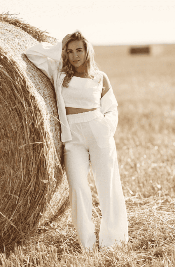 Pantalon blanc femme – coupe fluide taille haute été Femme portant un pantalon blanc fluide taille haute, tenue estivale élégante dans un champ