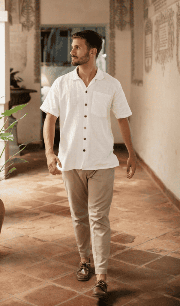 Homme portant un pantalon beige avec chemise blanche, style élégant et décontracté en intérieur